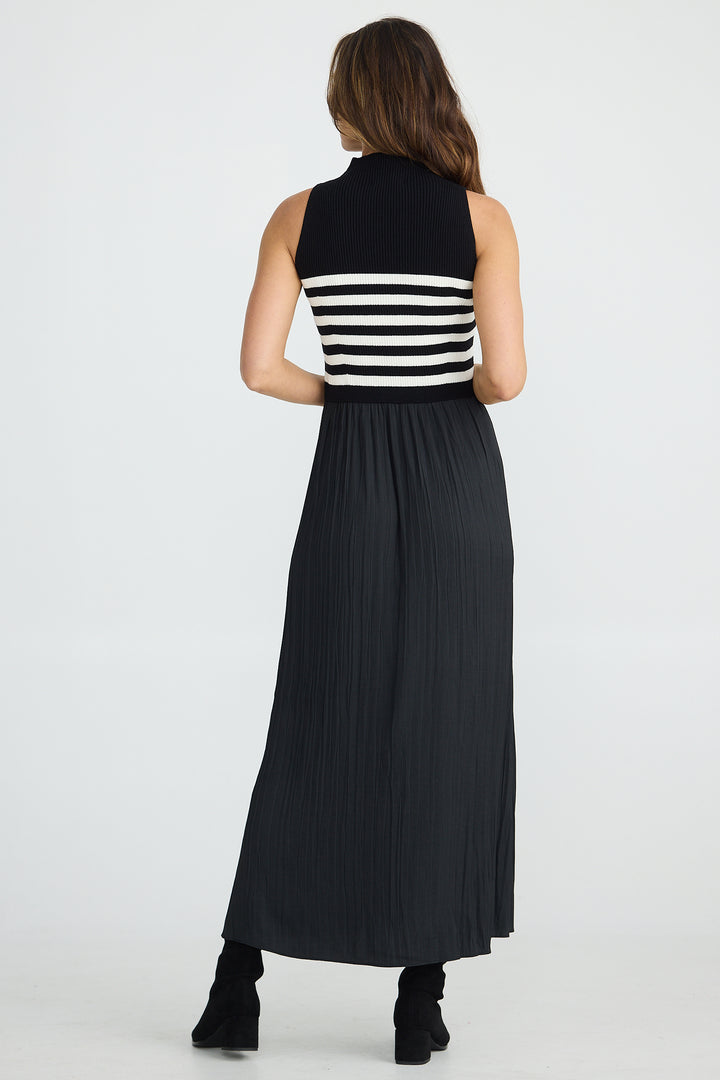 Woman wearing a black and white striped sleeveless top with a long black skirt on a white background