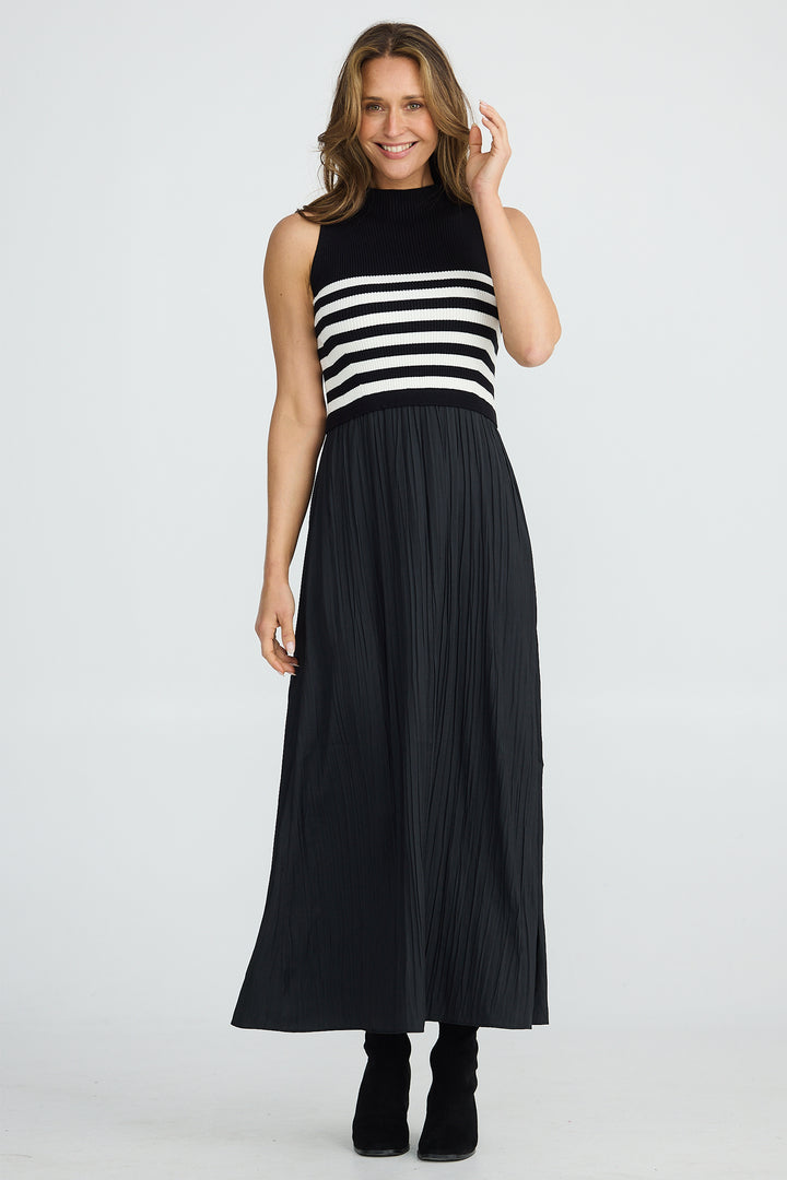 Woman wearing a black and white striped sleeveless top with a long black pleated skirt on a white background