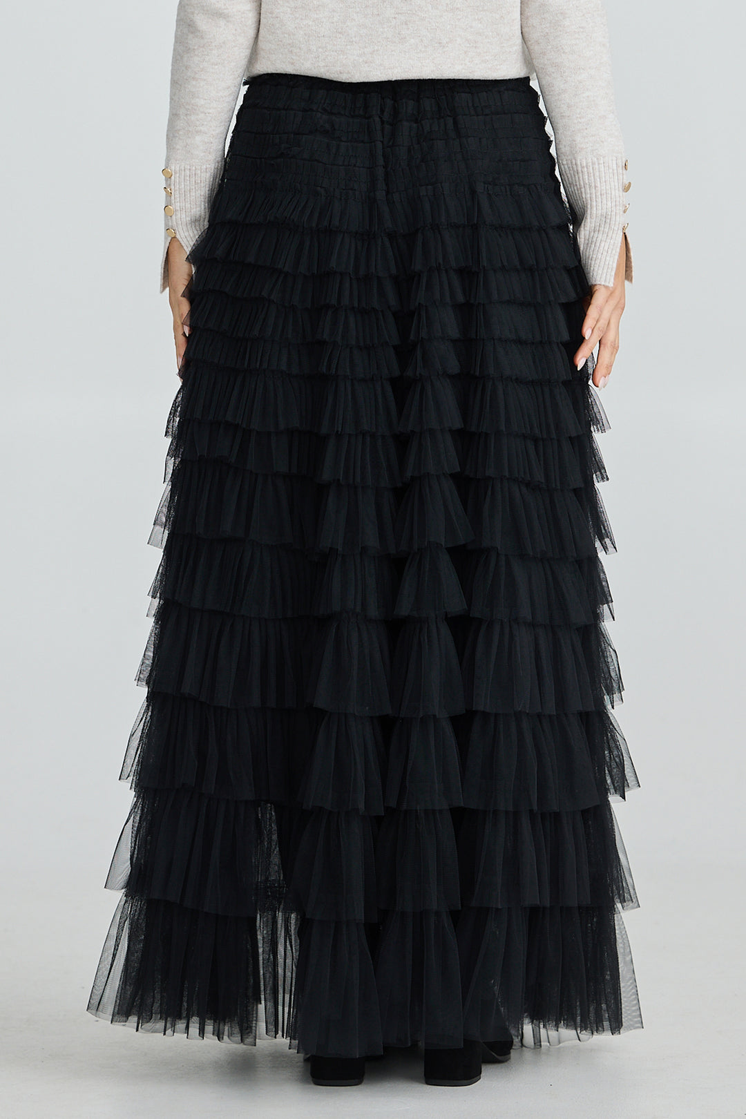 Black tiered skirt worn by a person on a white background