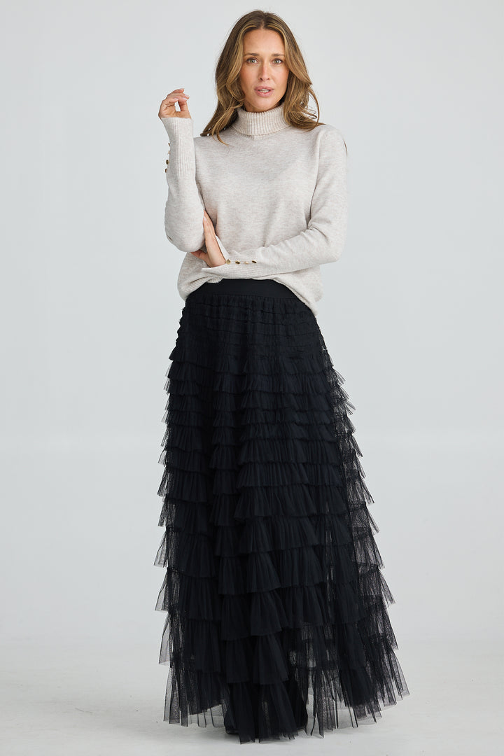 Woman wearing a black tiered skirt and light gray sweater on a white background
