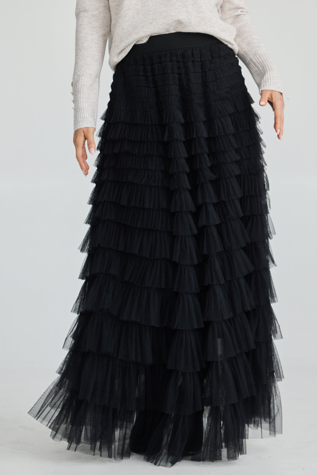 Black tiered tulle skirt worn by a person on a white background
