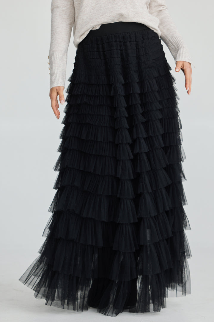 Black tiered tulle skirt worn by a person on a white background