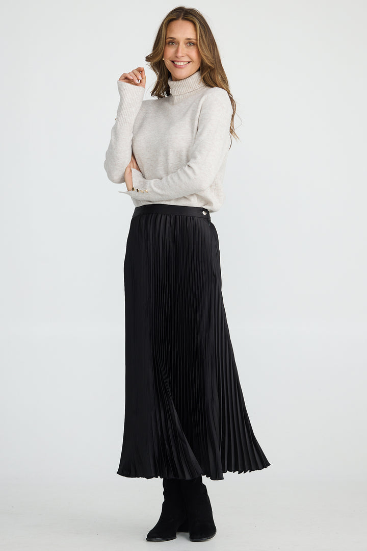 Woman wearing a white turtleneck sweater and black pleated skirt on a white background
