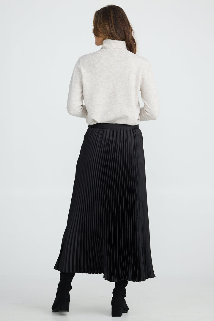 Person wearing a white blouse and black pleated skirt on a white background