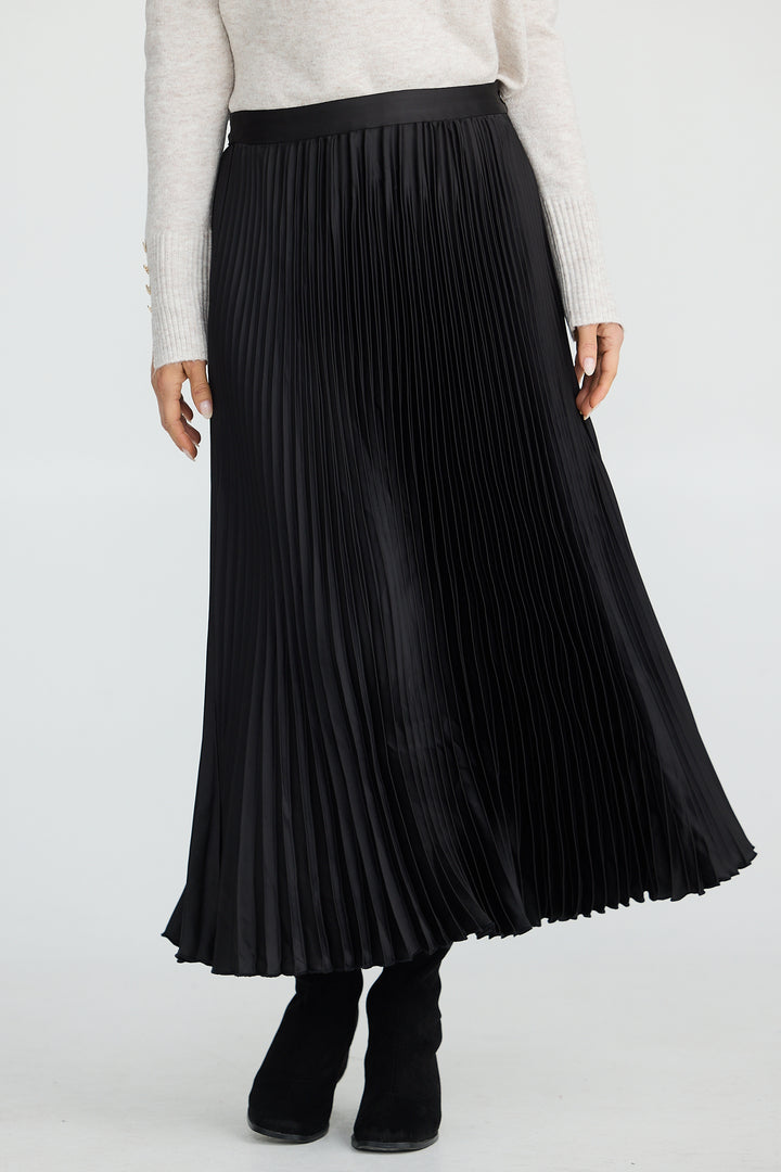 Person wearing a black pleated skirt and white top on a white background