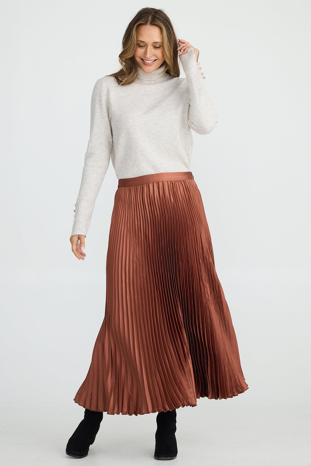 Woman wearing a white turtleneck sweater and brown pleated skirt on a white background