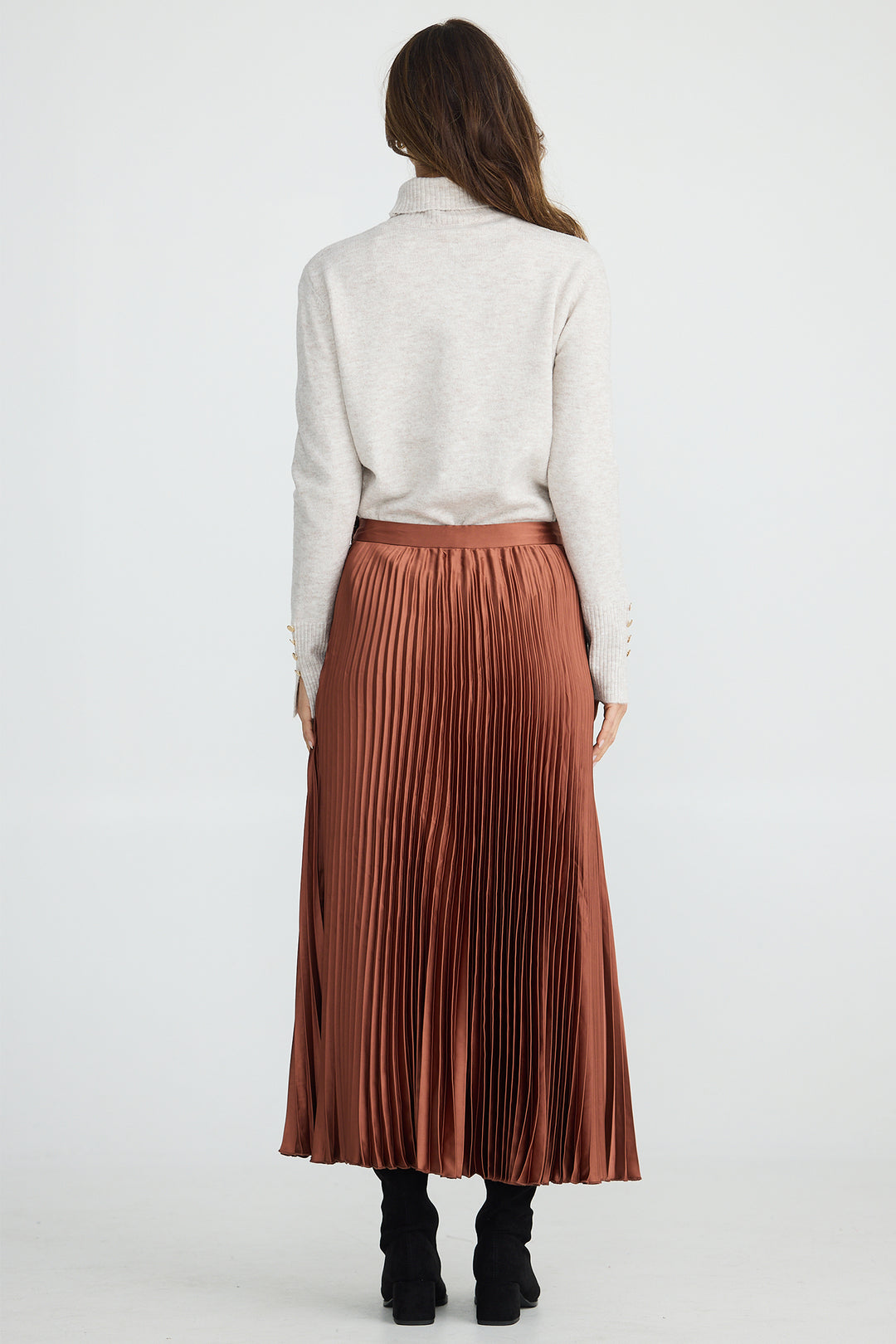 Person wearing a white shirt and brown pleated skirt on a white background