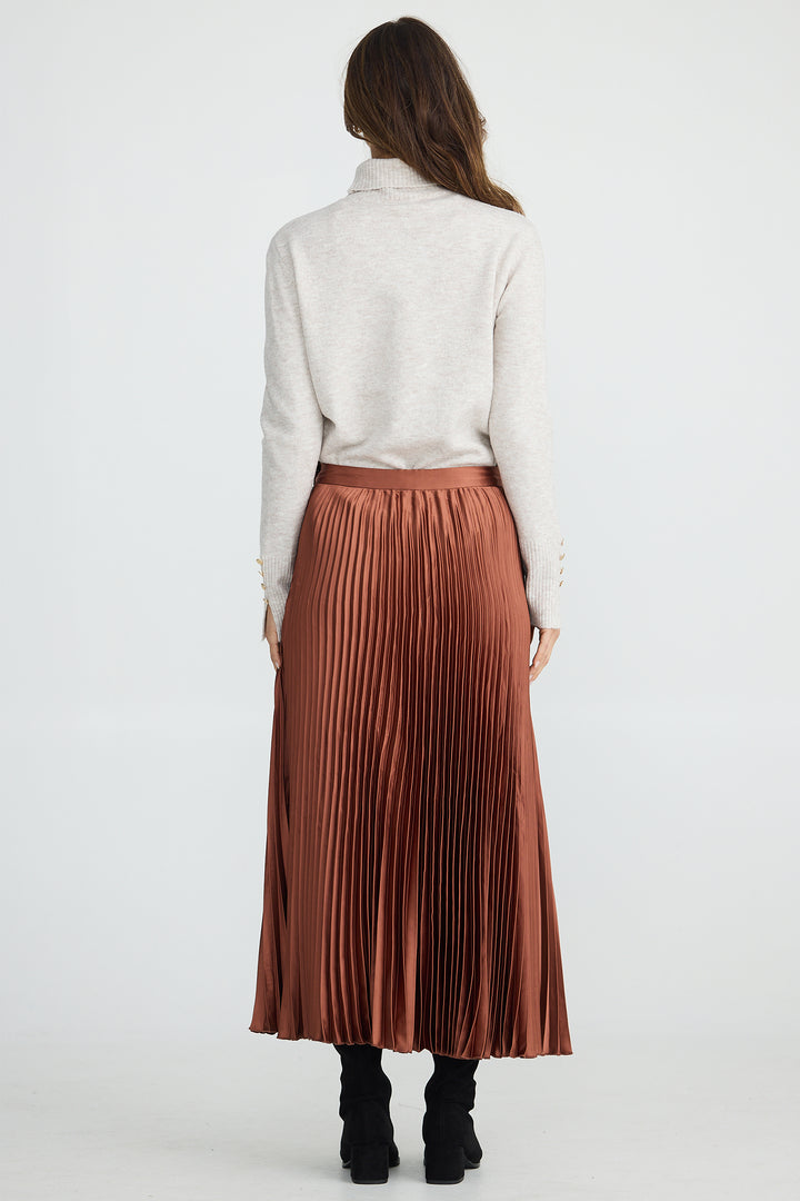 Person wearing a white shirt and brown pleated skirt on a white background