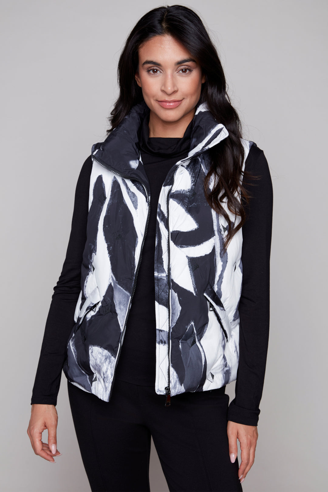 Woman wearing a black and white patterned vest against a plain background