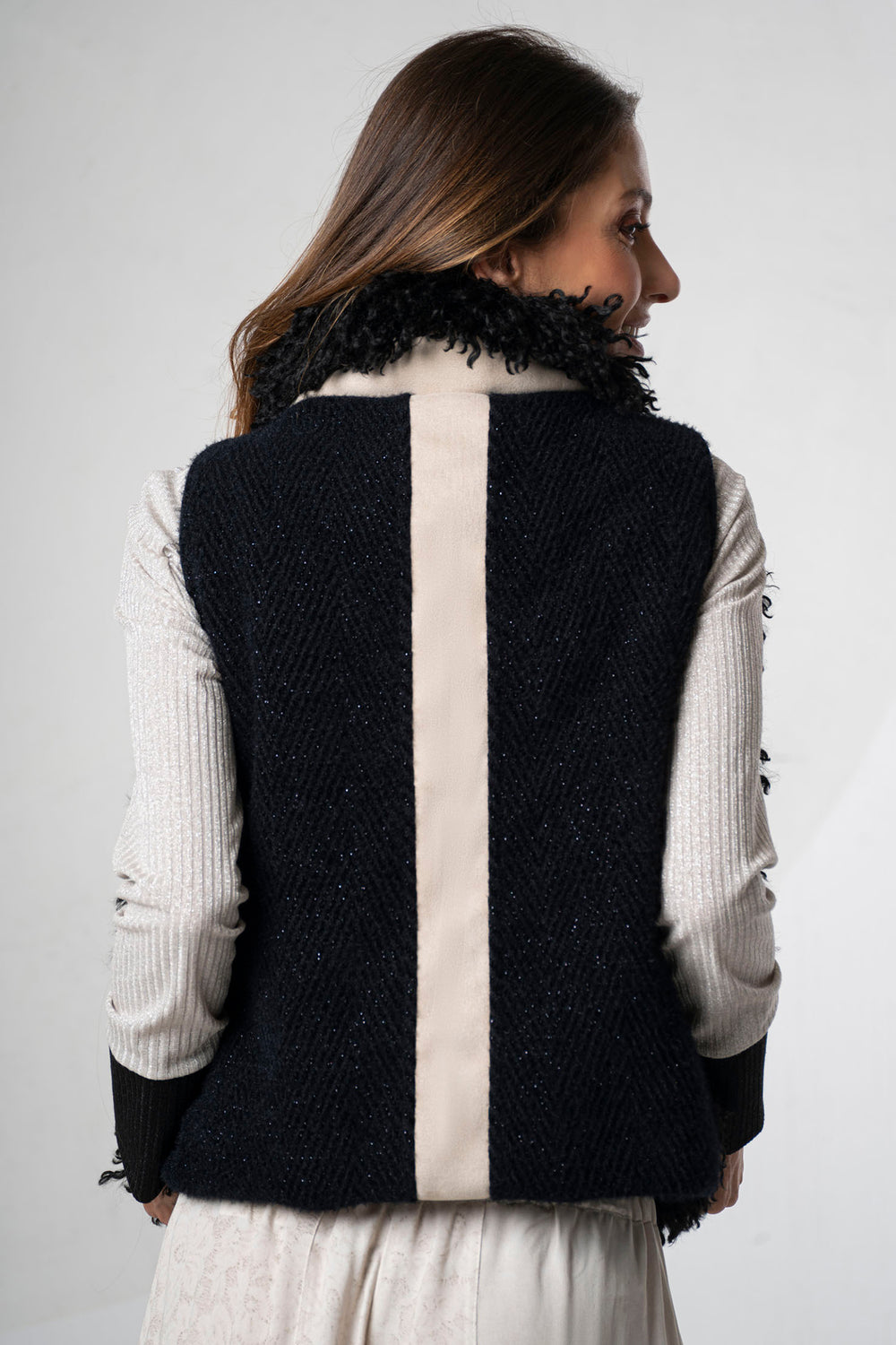 Woman wearing a black and white vest with fur collar on a plain background