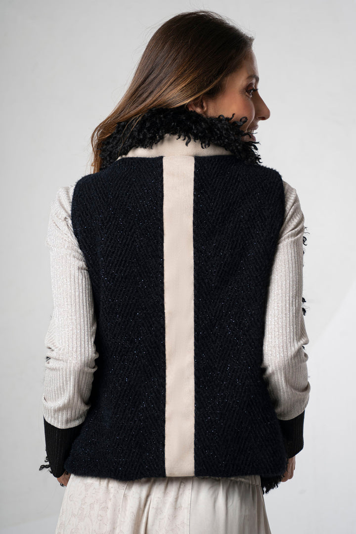 Woman wearing a black and white vest with fur collar on a plain background