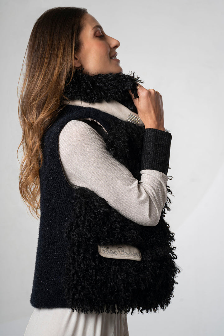 Woman wearing a black fringed vest over a white shirt on a plain background