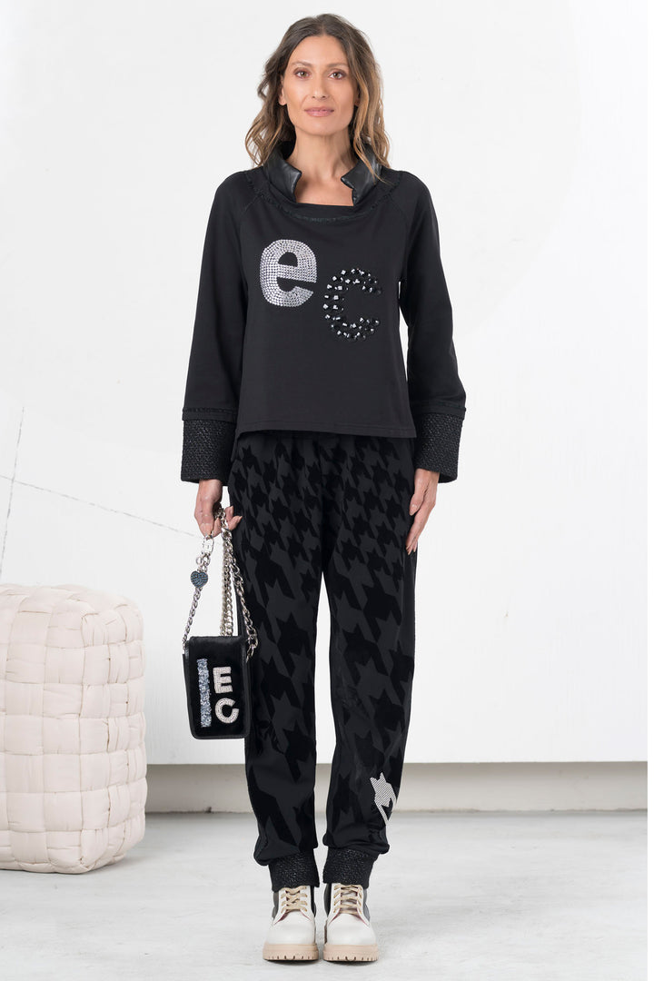 Woman wearing a black outfit with 'ecco' branding in a minimalistic setting