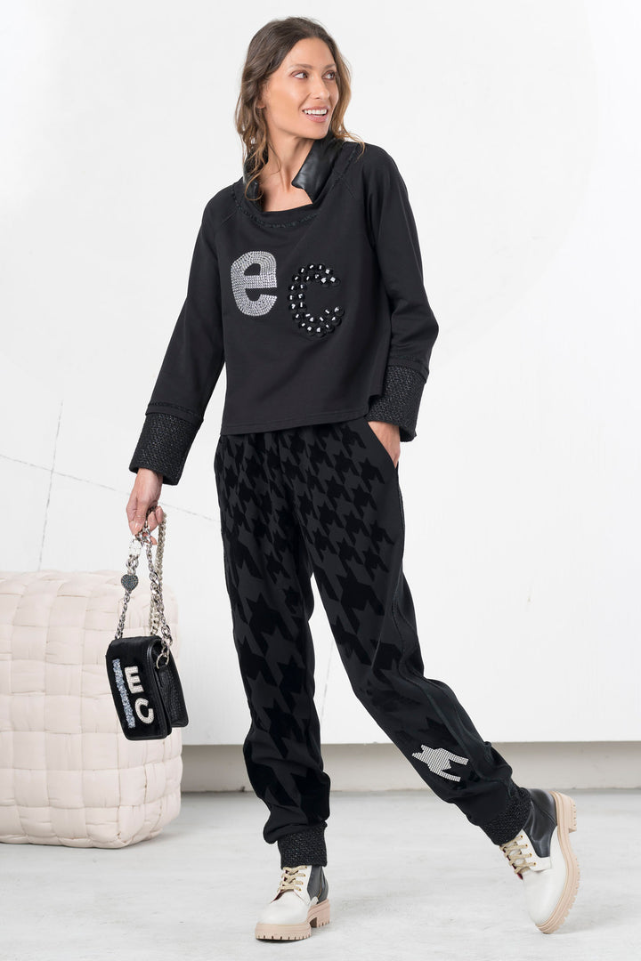 Woman wearing a black outfit with 'ec' branding, holding a matching bag.