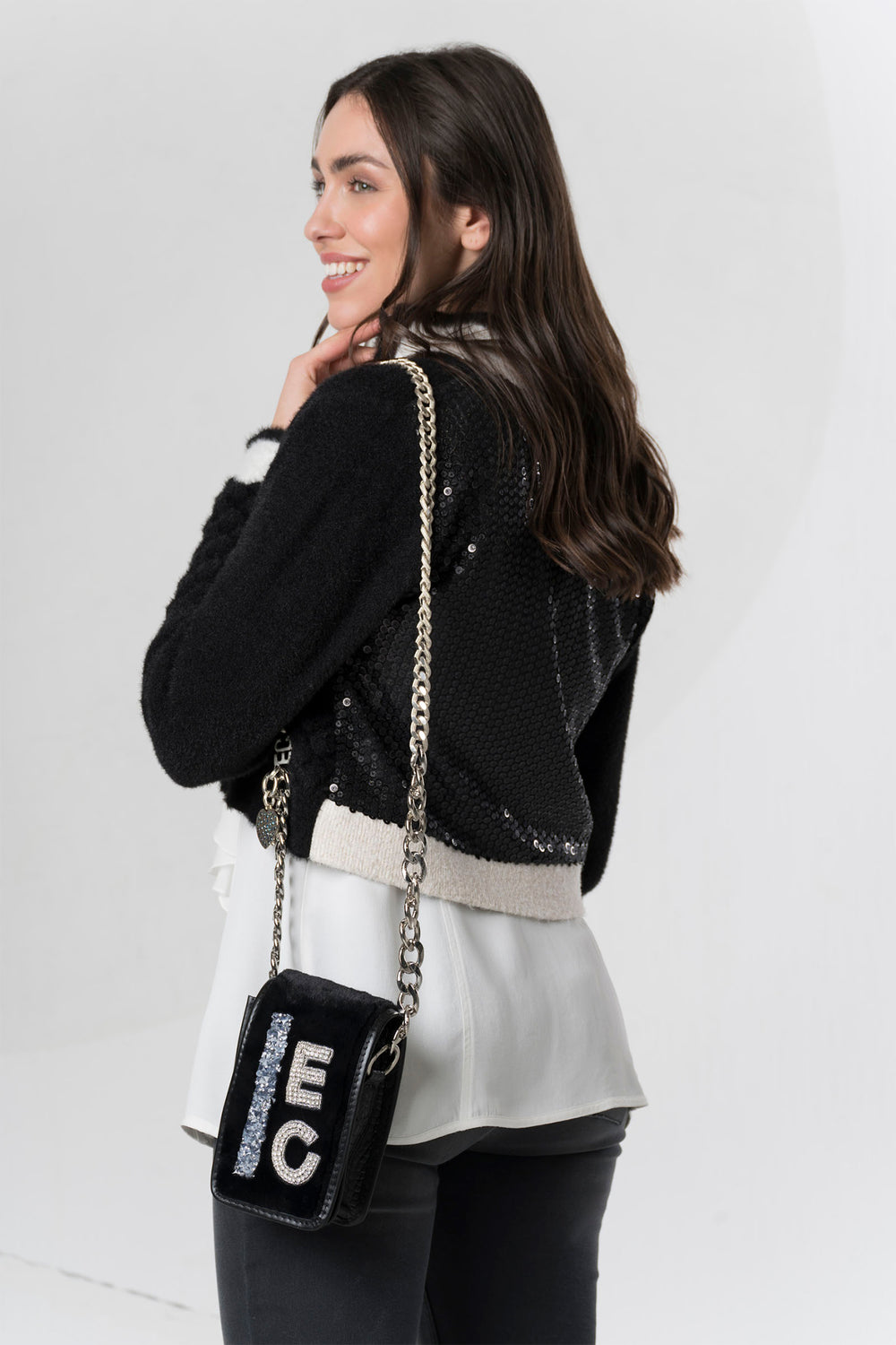 Woman carrying a black handbag with 'EC' branding against a white background