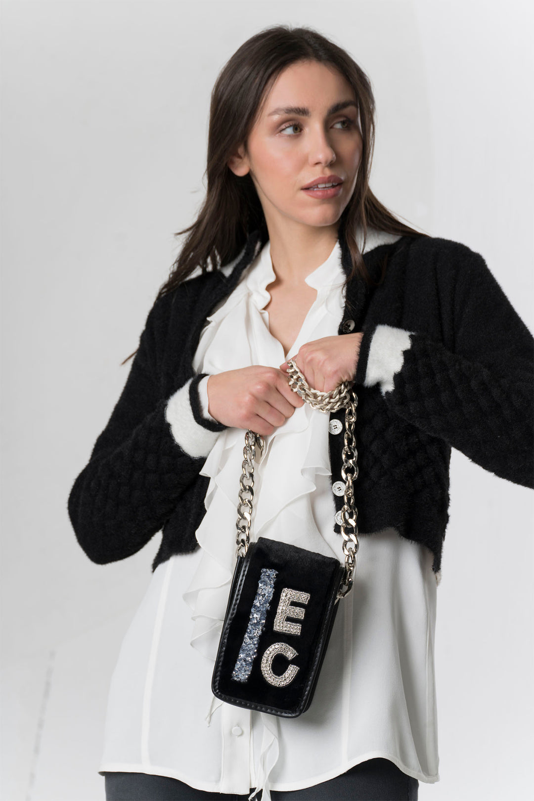 Woman holding a black handbag with 'EC' letters against a white background