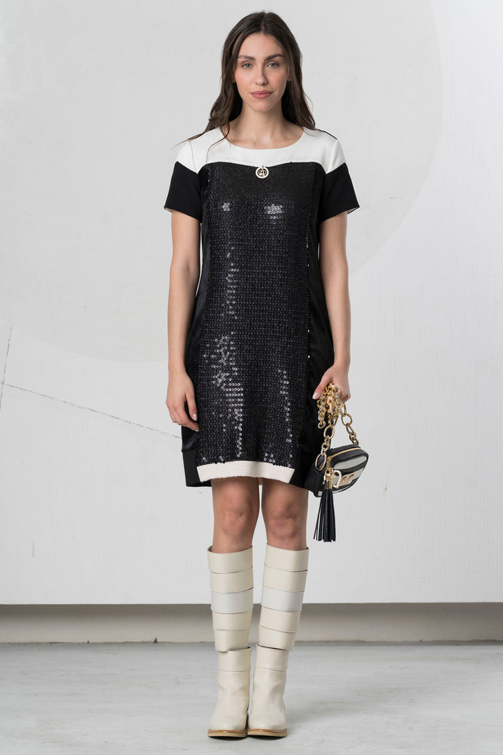 Woman wearing a black and white dress with knee-high boots against a white background