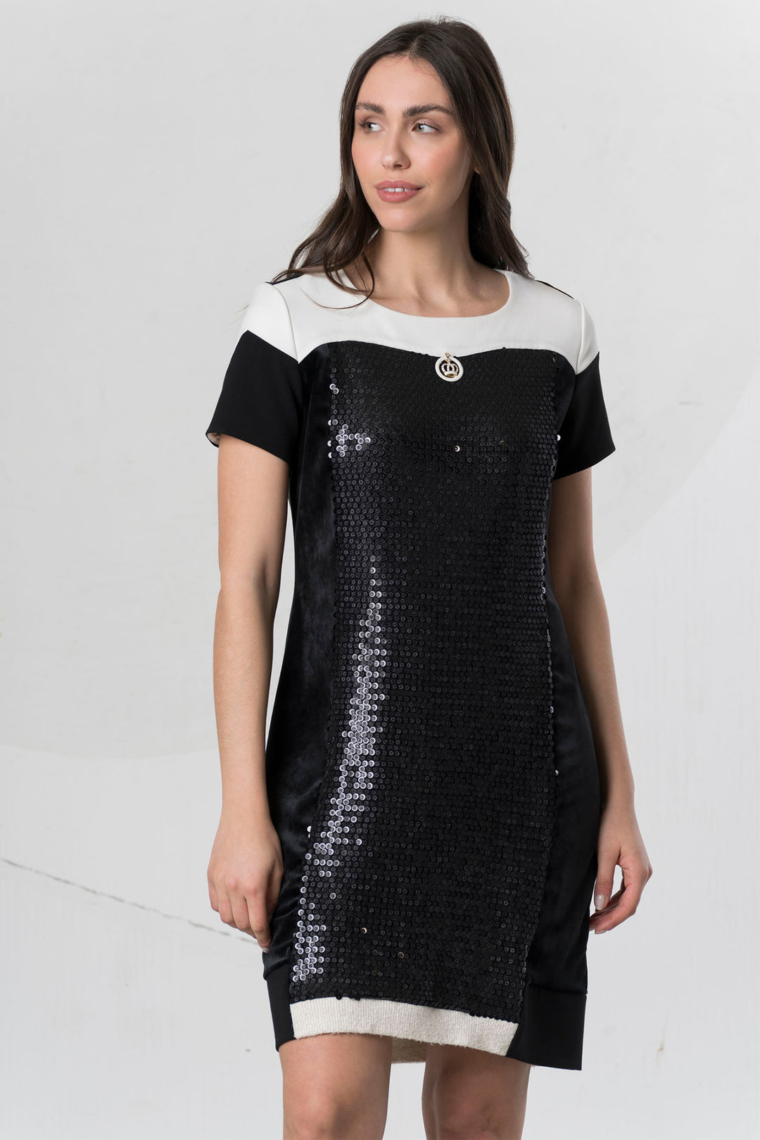 Woman wearing a black and white dress with sequin details on a light gray background