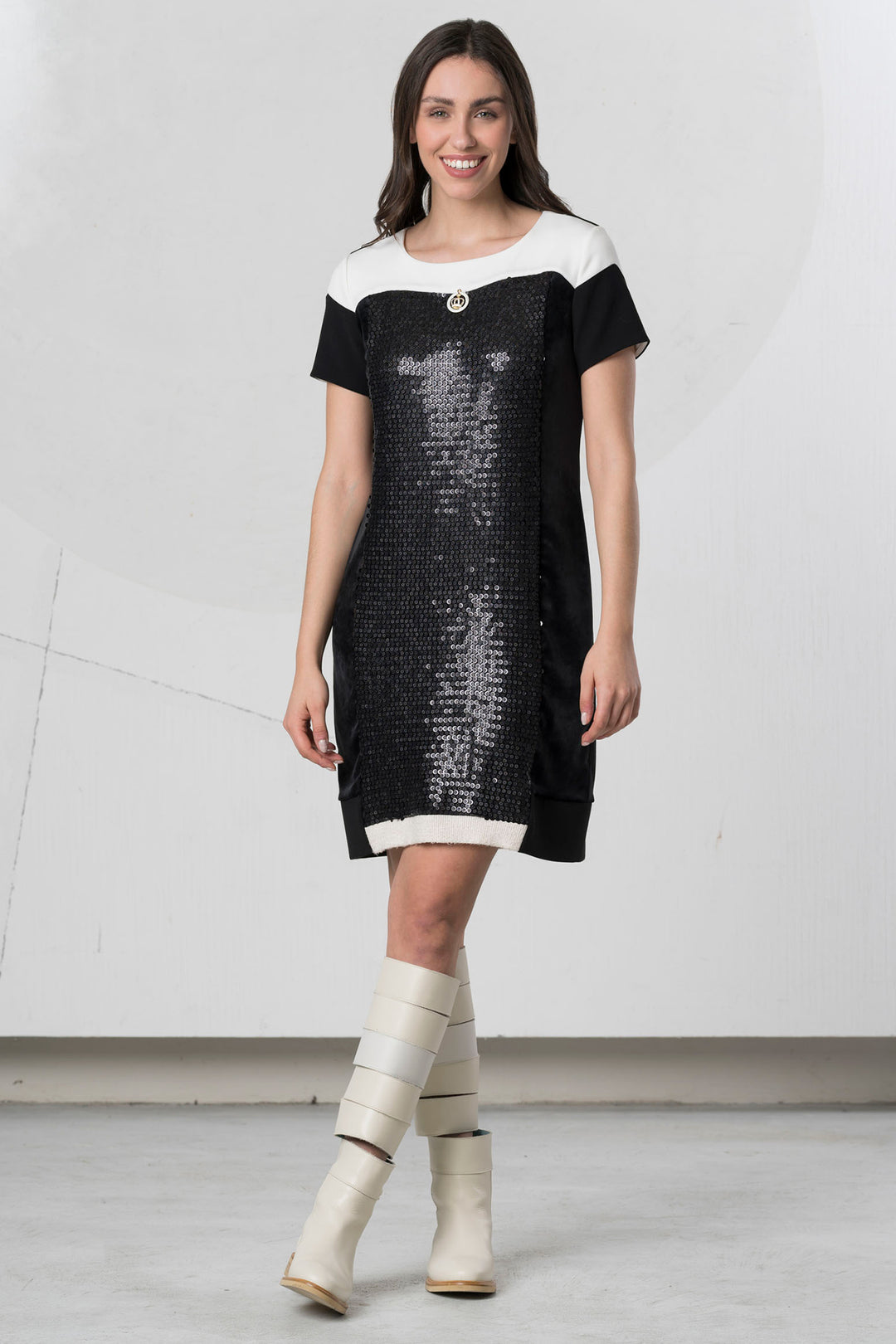 Woman wearing a black and white dress with sequin details on a plain background