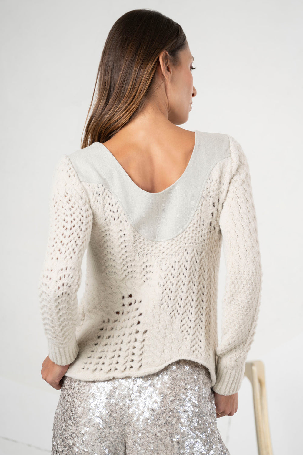 Woman wearing a beige sweater with a white background