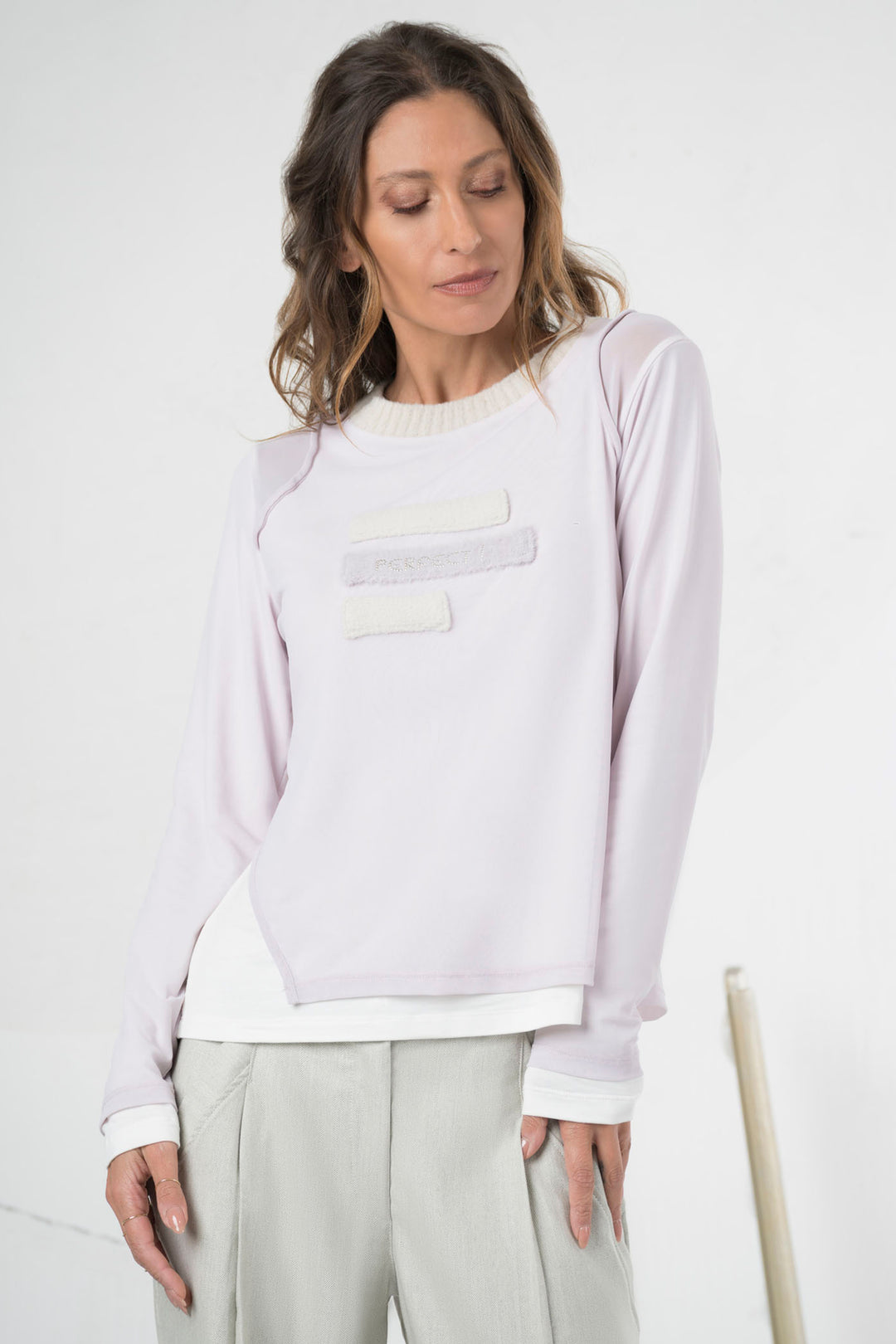 Woman wearing a light purple long-sleeve top with a white pocket on a white background
