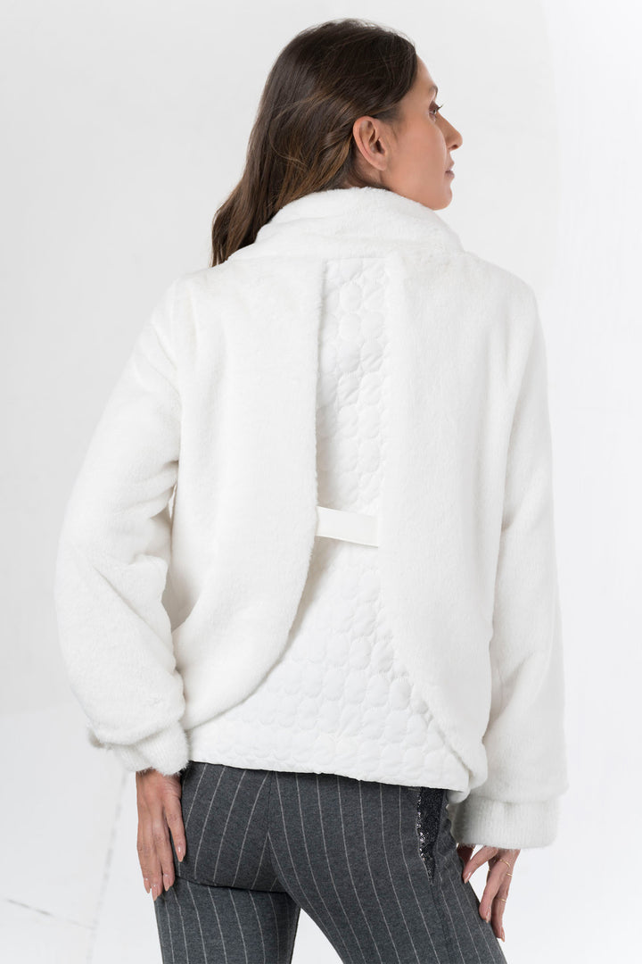 Woman wearing a white quilted jacket on a plain background