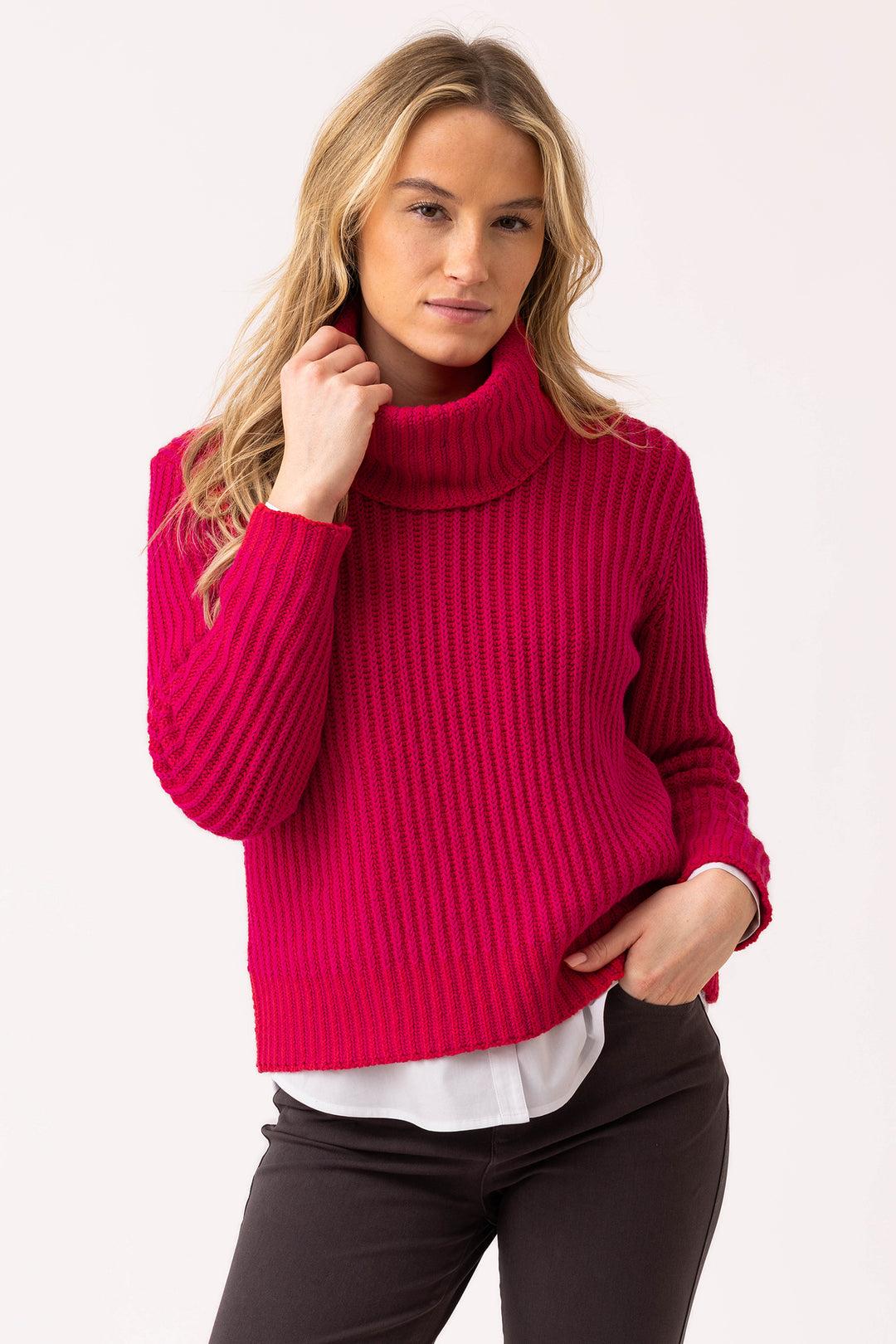 Woman wearing a bright pink turtleneck sweater on a white background
