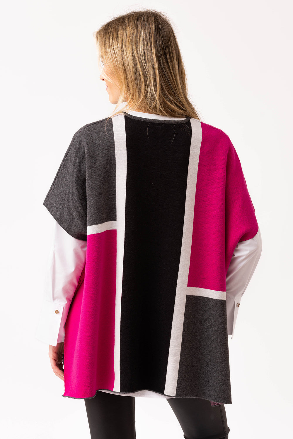 Woman wearing a colorful poncho with geometric pattern on a white background