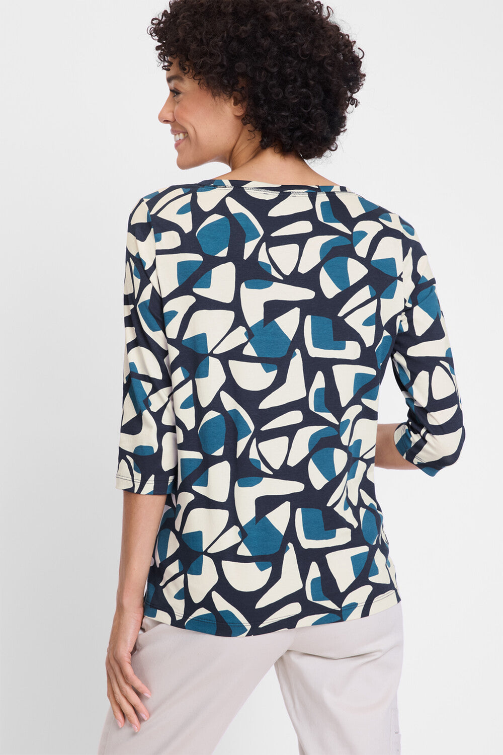 Woman wearing a patterned blouse with abstract design on a white background