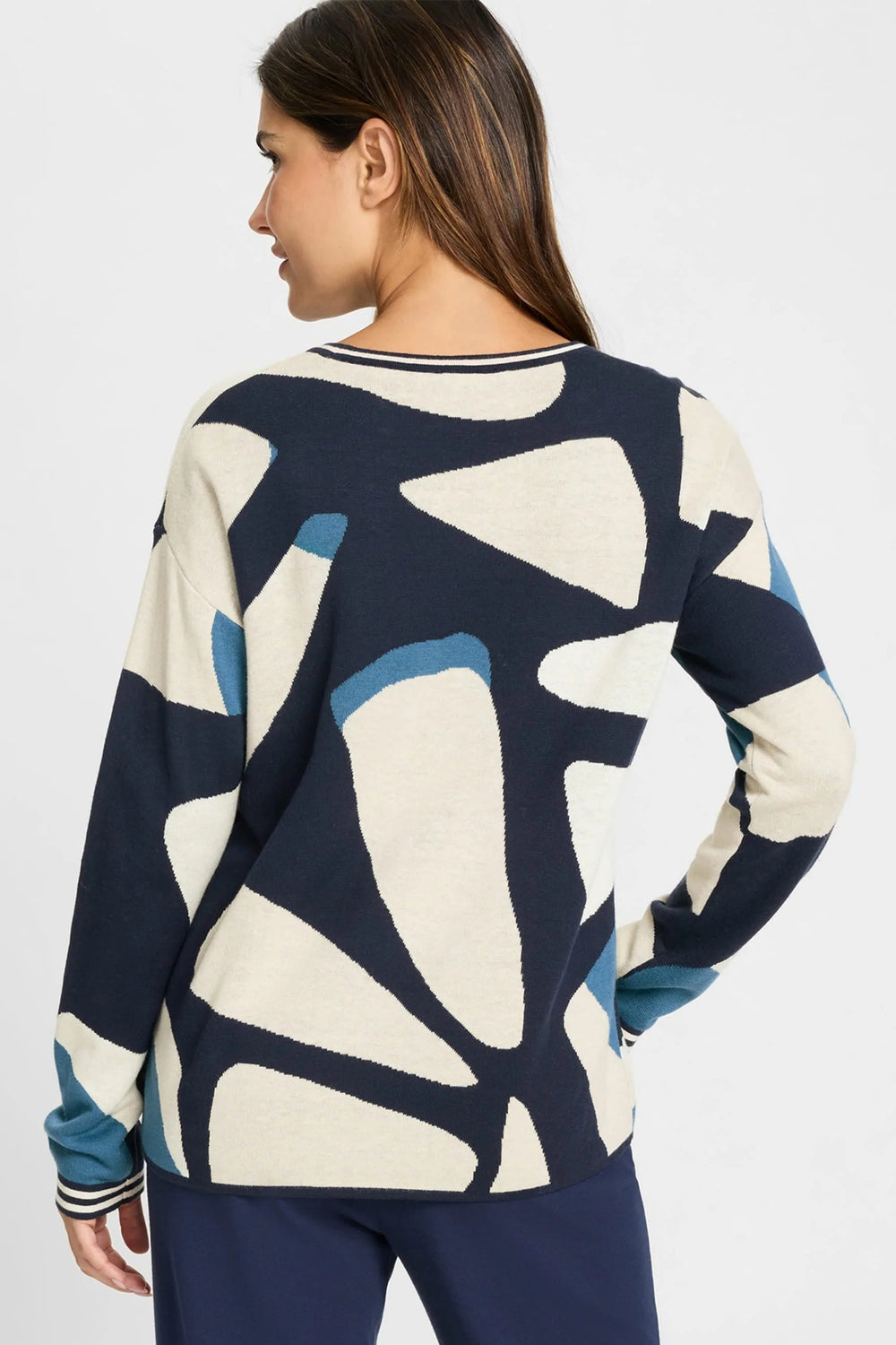 Woman wearing a navy and white abstract patterned sweater on a white background