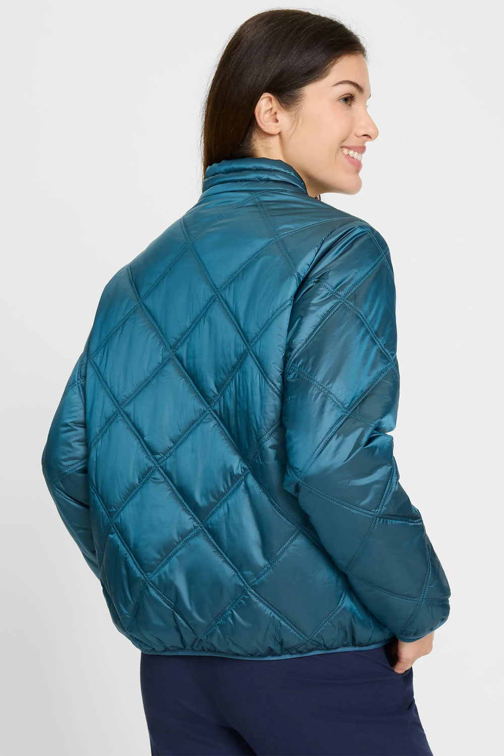Woman wearing a teal quilted jacket on a white background