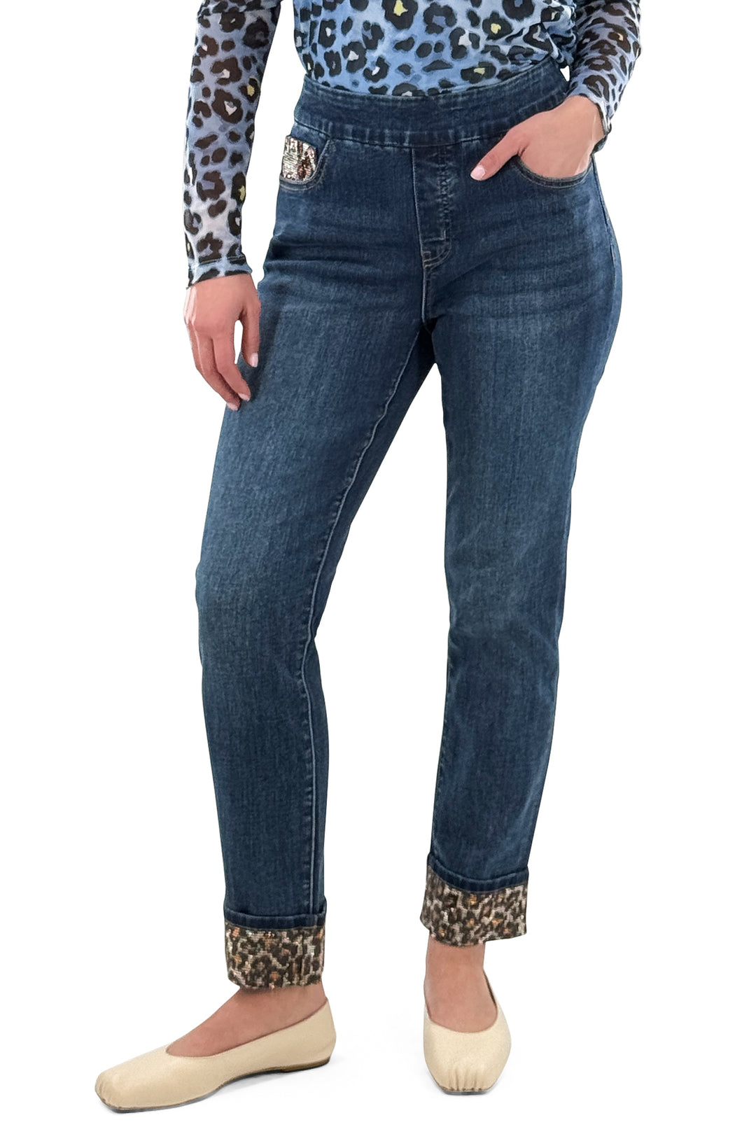 Person wearing blue jeans with leopard print cuffs on a white background