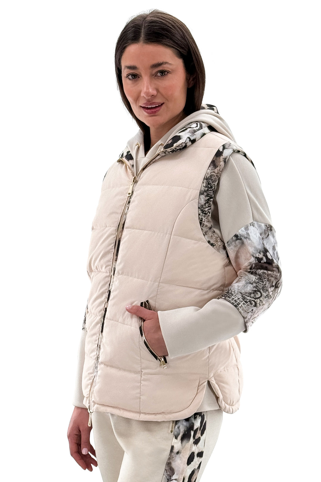 Woman wearing a cream-colored puffer vest with patterned sleeves on a white background