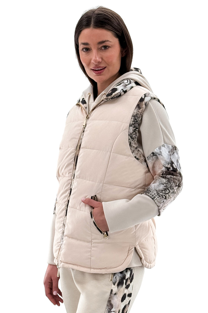 Woman wearing a cream-colored puffer vest with patterned sleeves on a white background