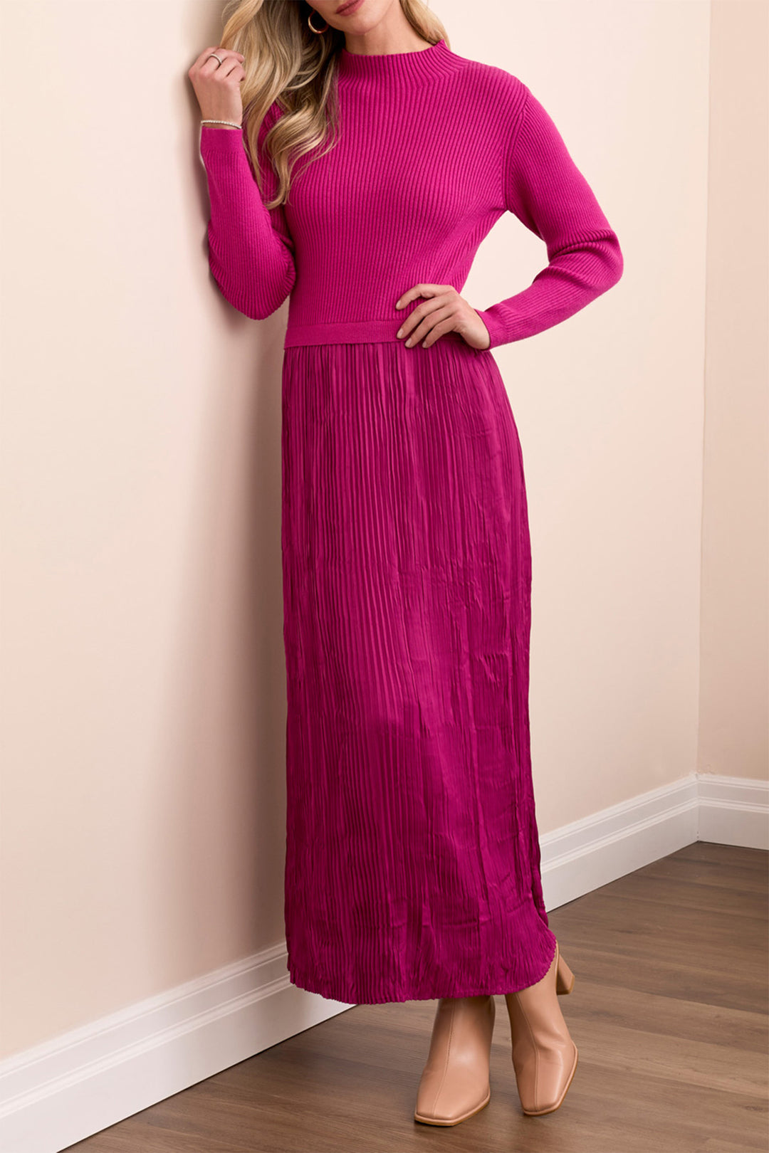 Woman wearing a pink long-sleeve dress against a beige wall.