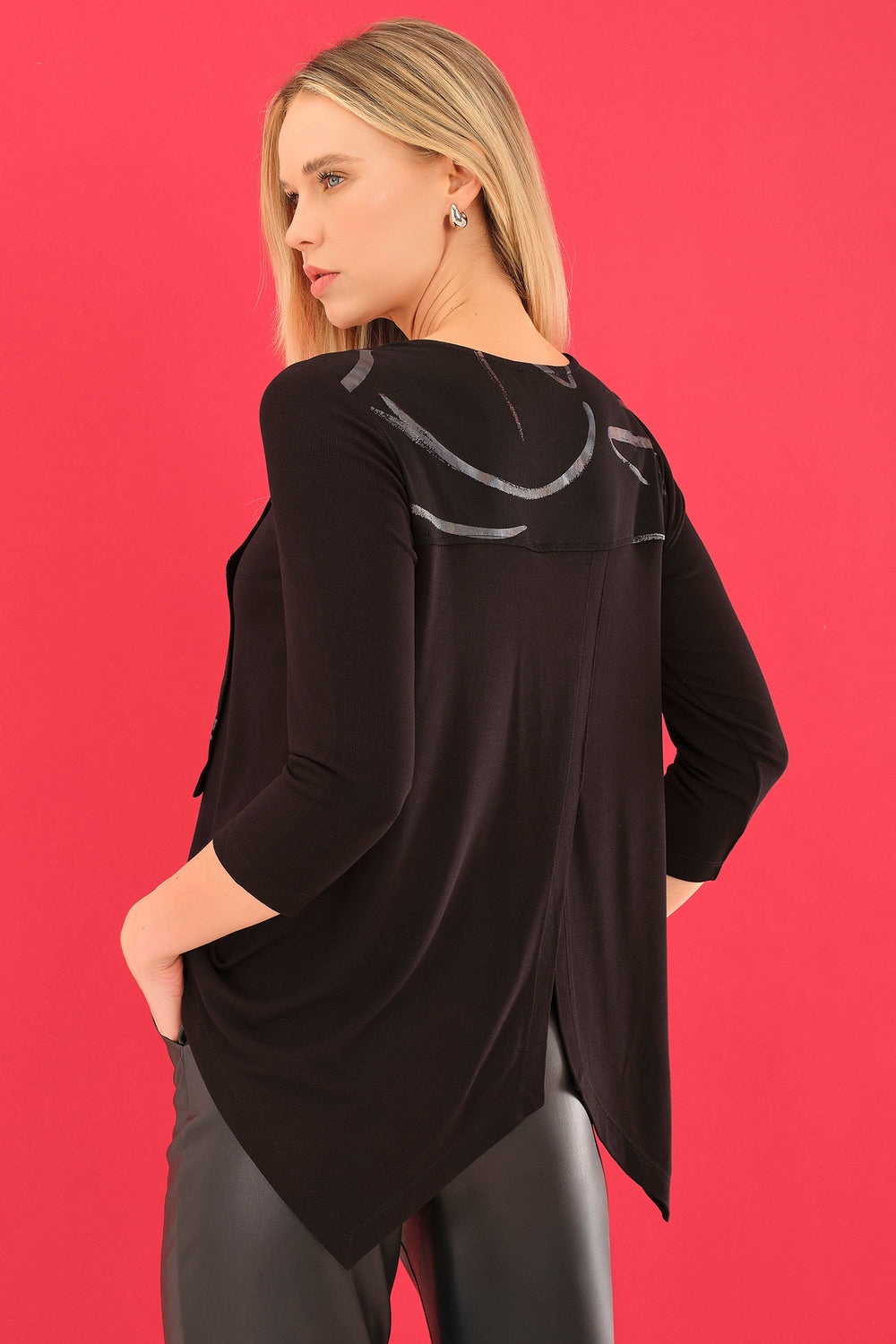 Woman wearing a black outfit with a unique design on a red background