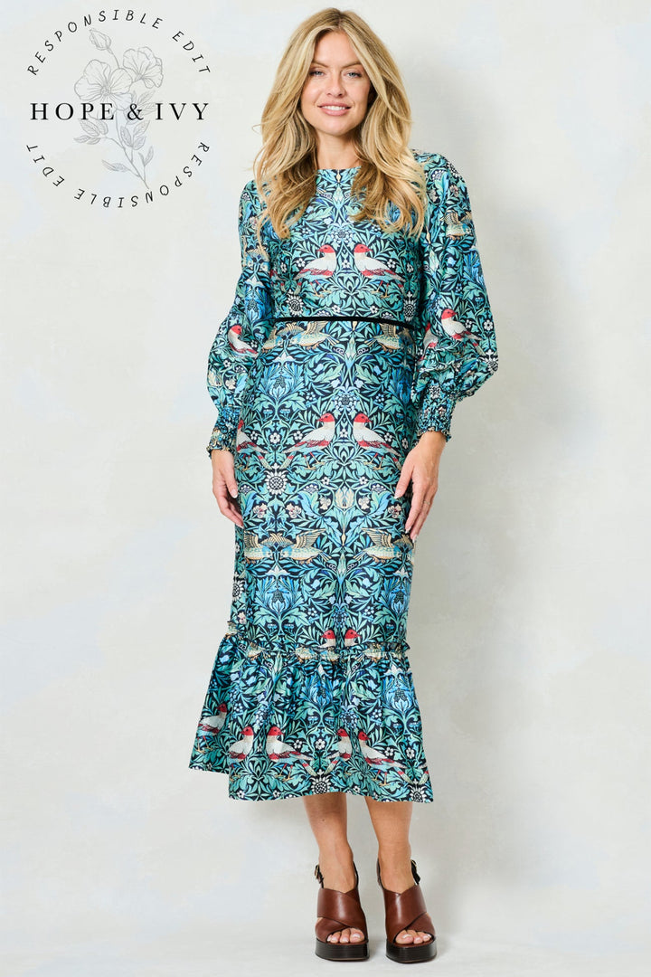 Woman wearing a blue floral dress with a white background, featuring the brand 'Hope & Ivy'.