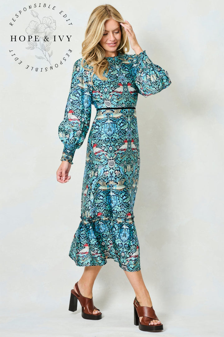 Woman wearing a floral dress with a white background, featuring the brand 'Hope & Ivy'.