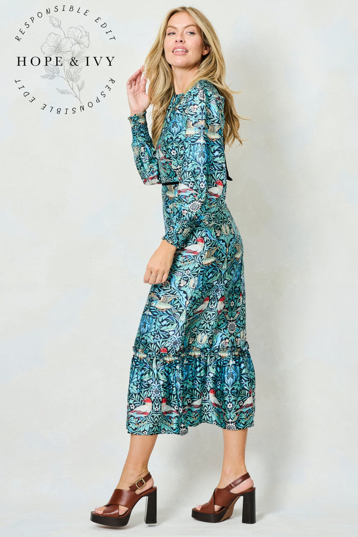 Woman wearing a floral dress with 'Hope & Ivy' branding on a white background