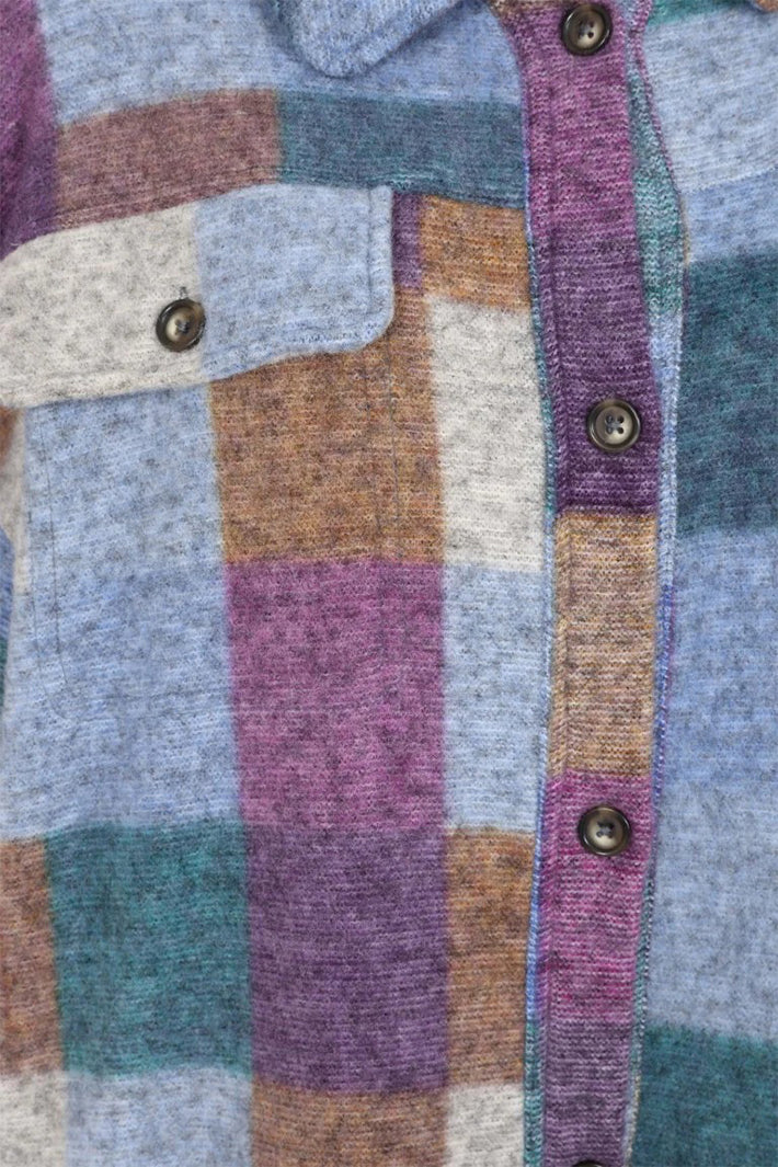 Close-up of a patchwork shirt with colorful squares and buttons.