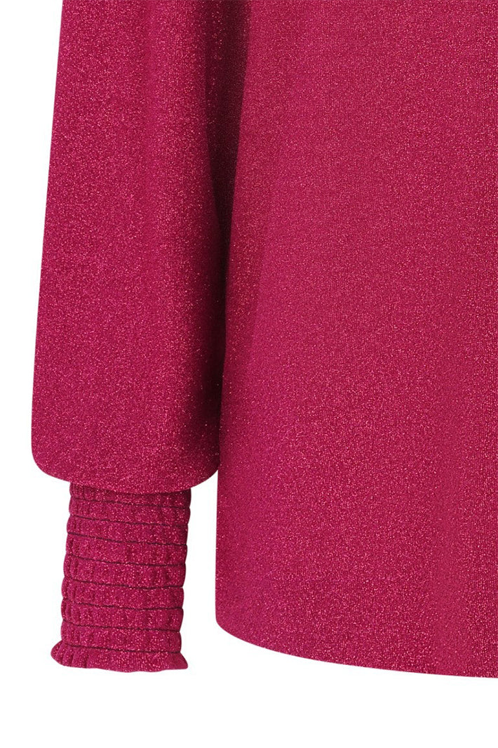 Close-up of a magenta sweater with textured fabric and ribbed cuffs on a white background