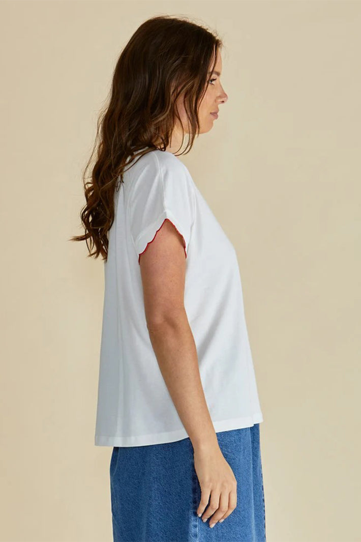 Woman wearing a white t-shirt and blue jeans against a beige background