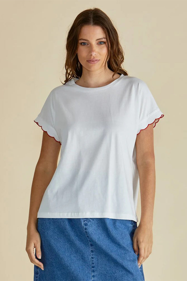 Woman wearing a white t-shirt with red trim on a beige background