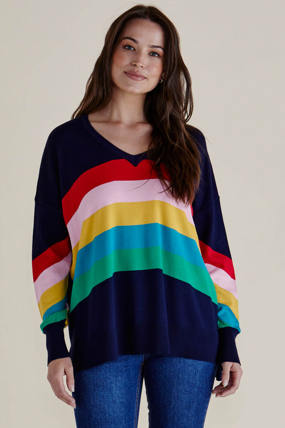 Woman wearing a colorful striped sweater with a plain background
