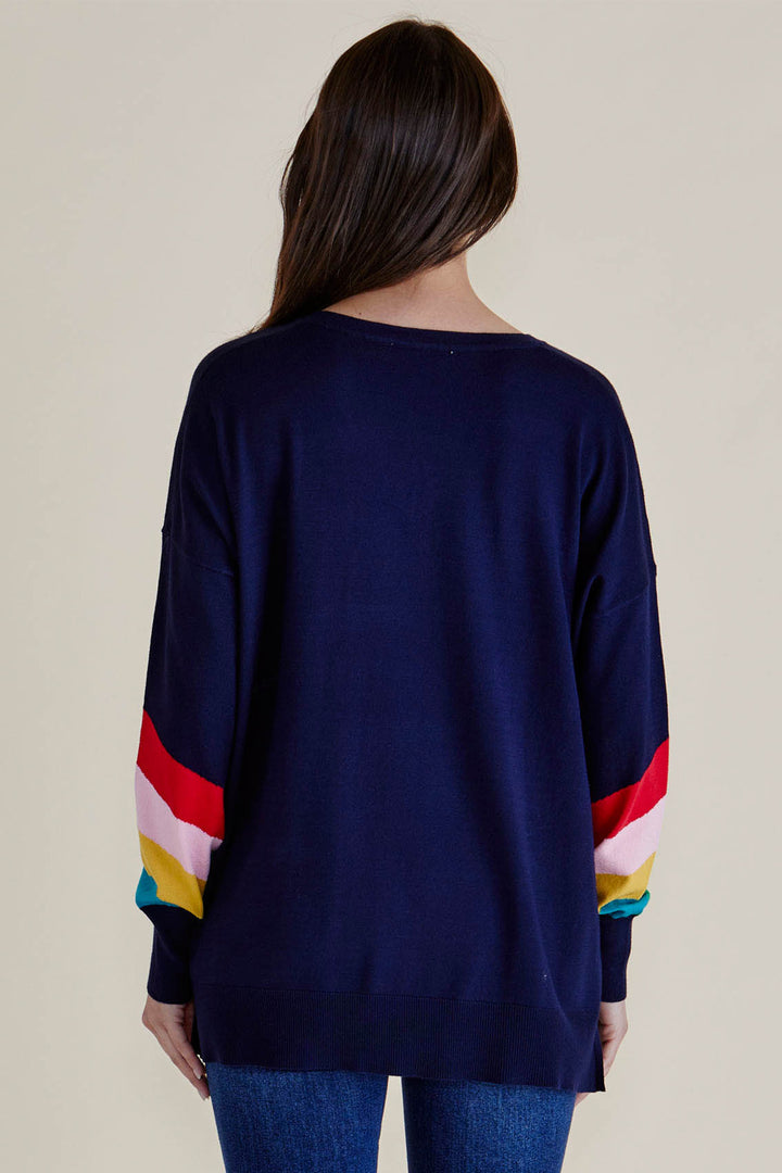 Navy sweater with colorful sleeves worn by a person on a beige background