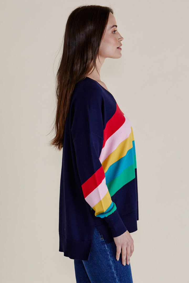 Woman wearing a navy sweater with a colorful striped pattern on a beige background