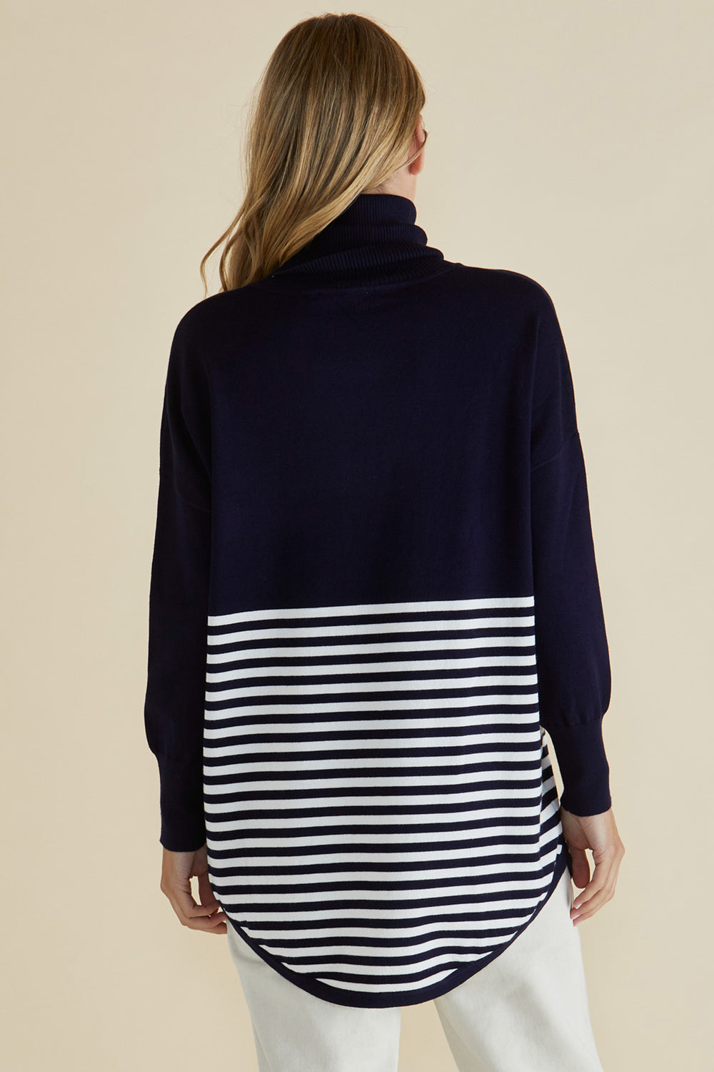 Navy sweater with a white striped pattern worn by a person on a beige background