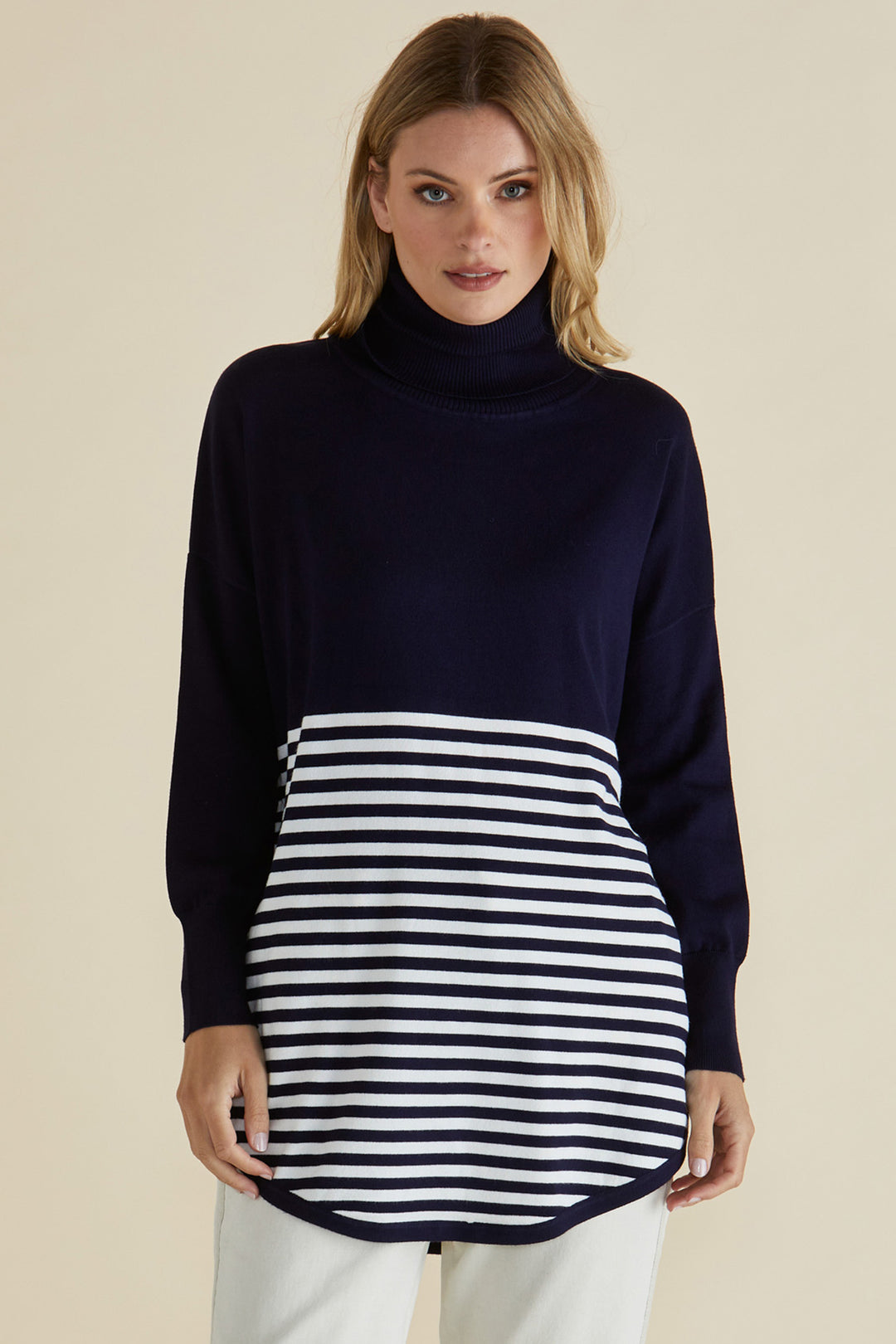 Woman wearing a navy sweater with a striped apron on a beige background