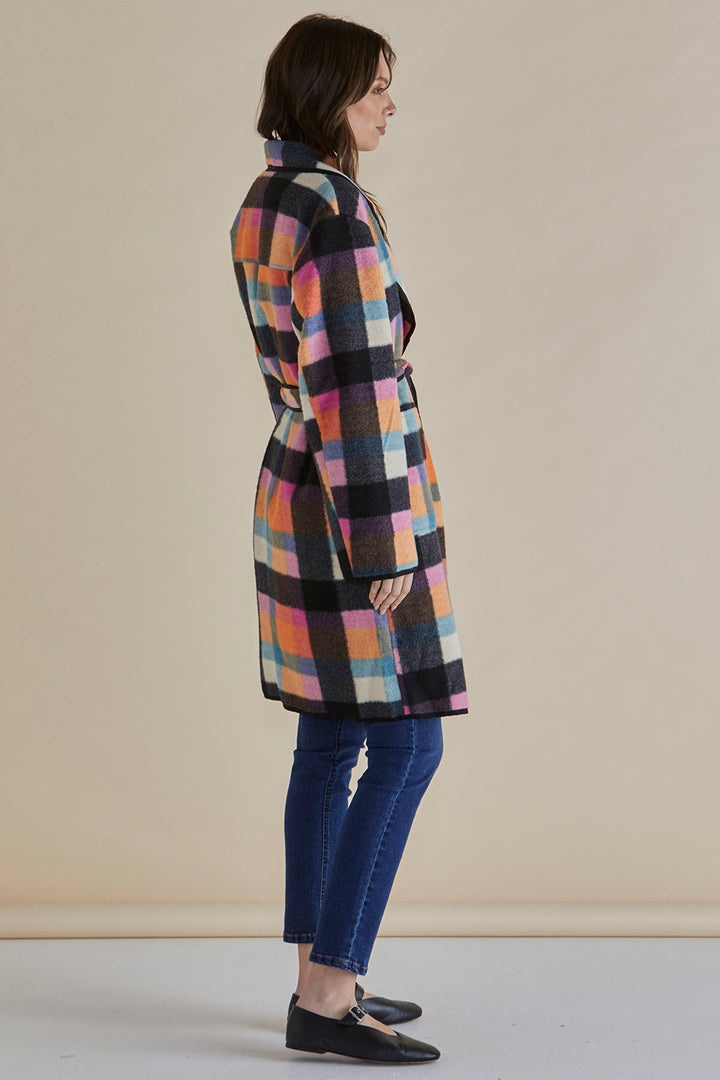 Woman wearing a multicolored checkered coat against a beige background