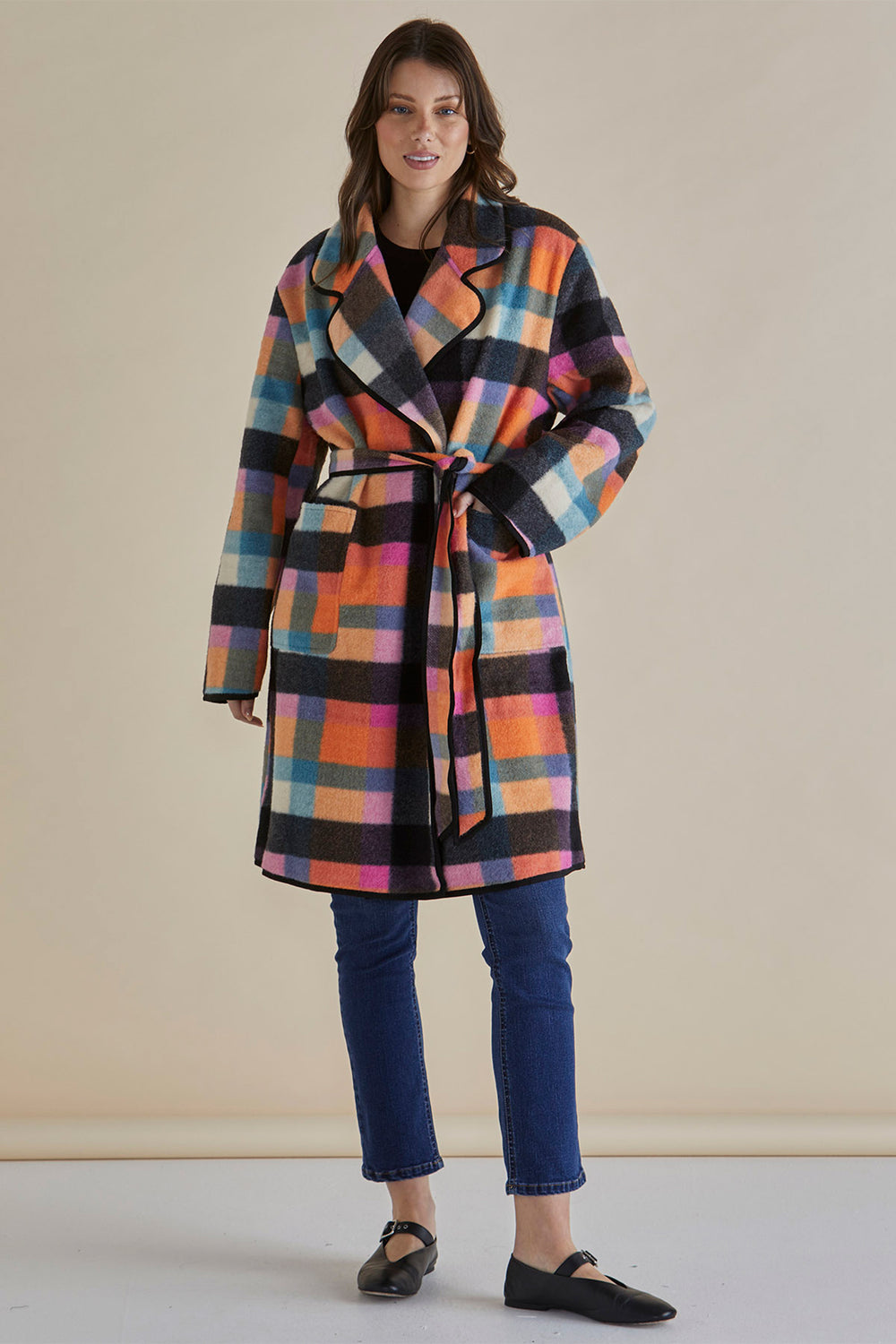 Woman wearing a colorful checkered coat against a beige background